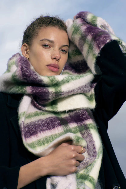 close up of woman wearing large green, purple and white scarf with soft fluffy material