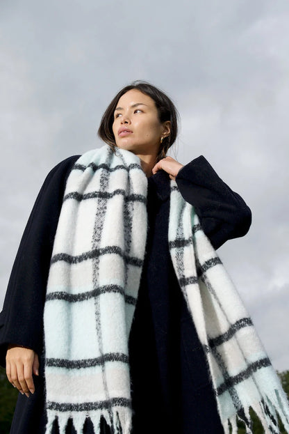 woman wearing chunky light blue, white and black plaid scarf with soft fluffy material, in winter