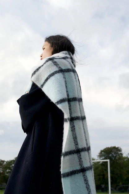woman wearing chunky light blue, white and black plaid scarf with soft fluffy material, in winter
