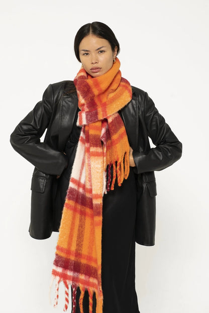 woman wearing oversized orange plaid scarf with tassels